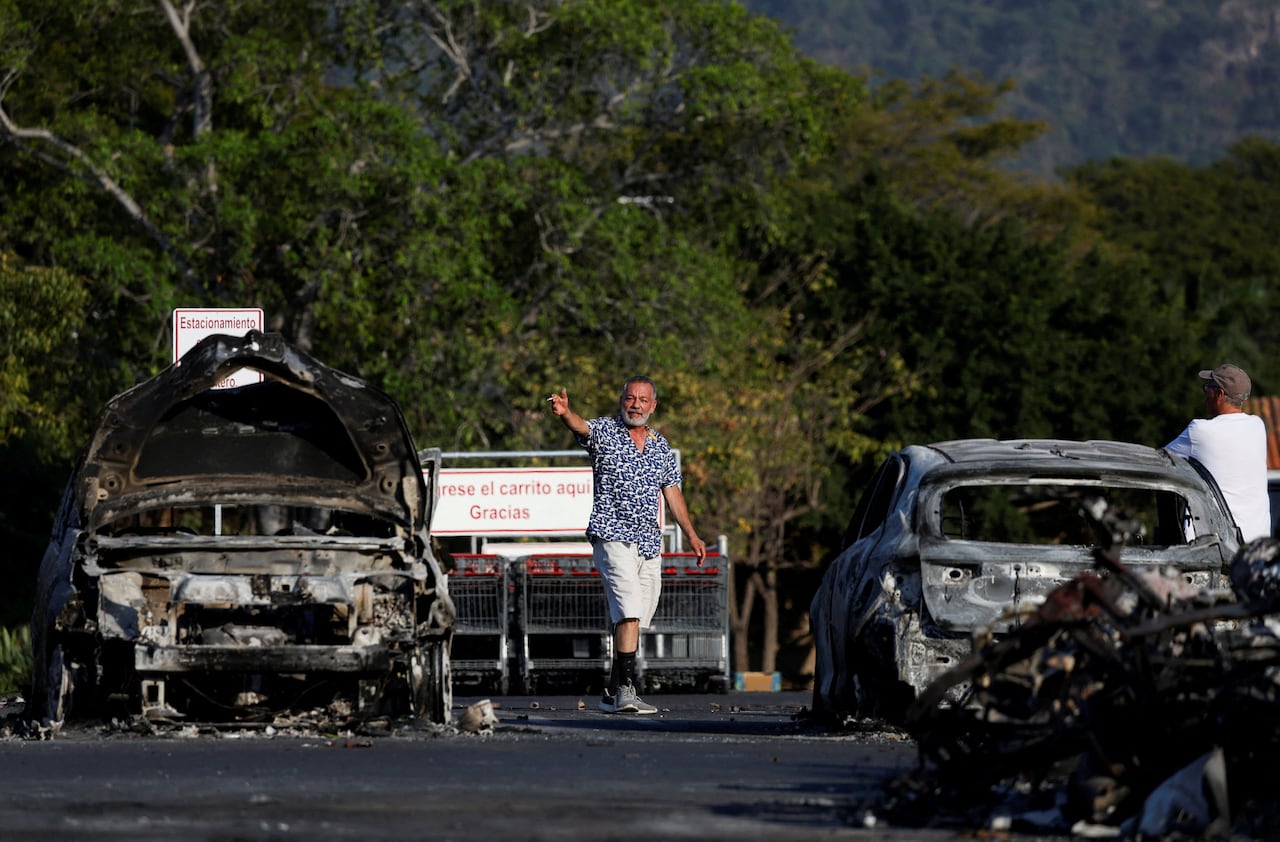 People are seen near burned-out cars outside of a supermarket in Puerta Vallarta, Mexico
