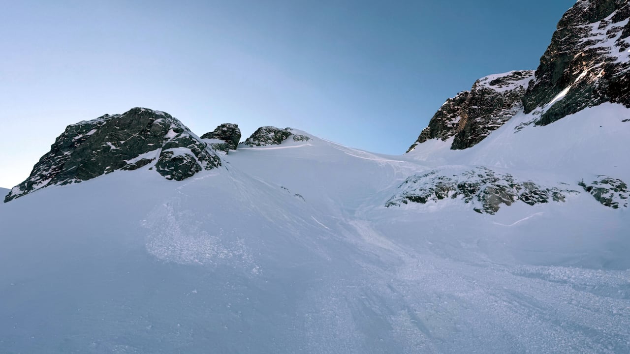 A mountain peak with snow and an avalanche path