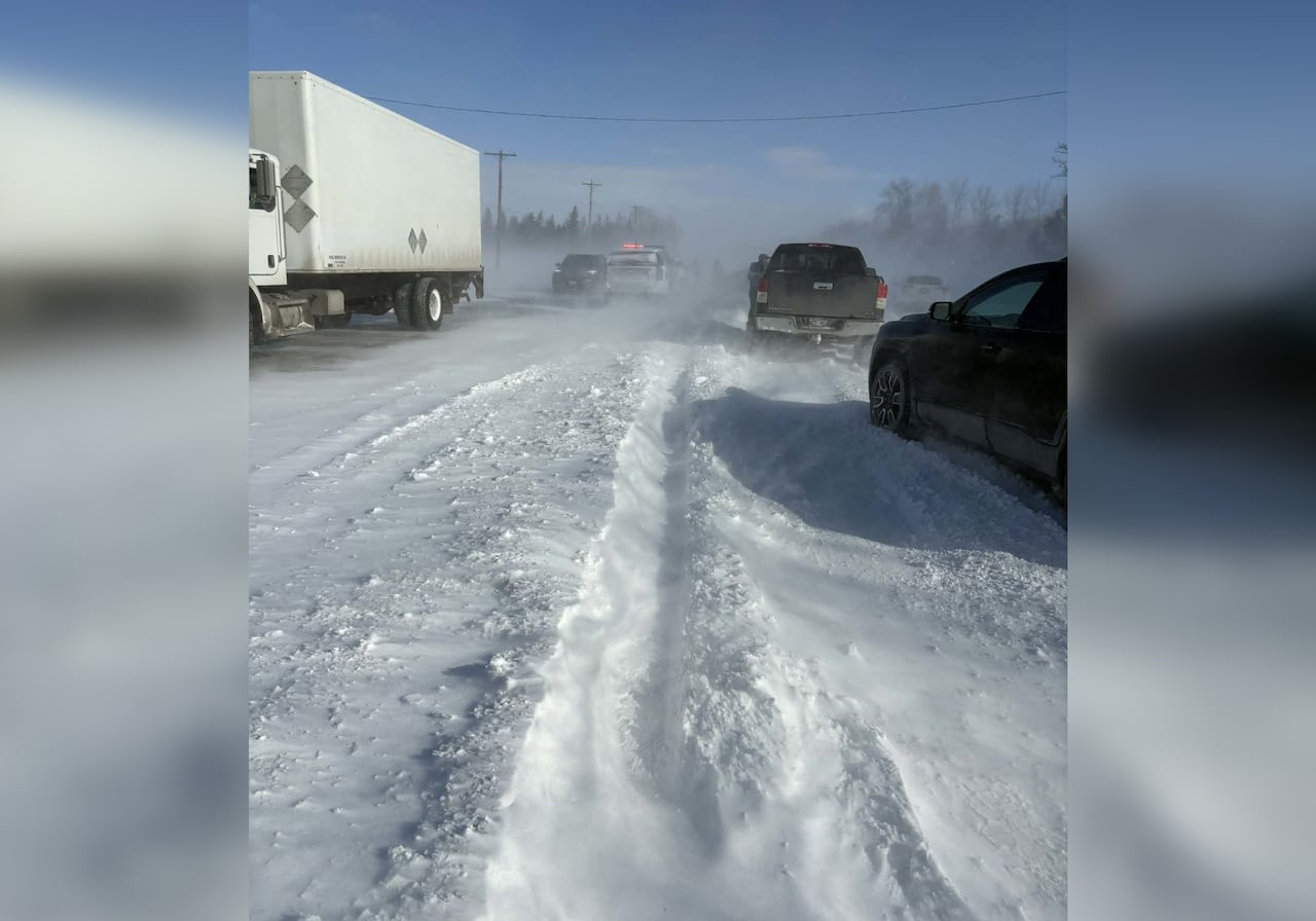 Several vehicles and a semi-trailer are seen stuck on a snowy highway