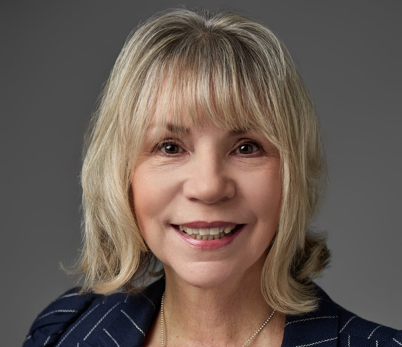 A woman in a blazer smiling.