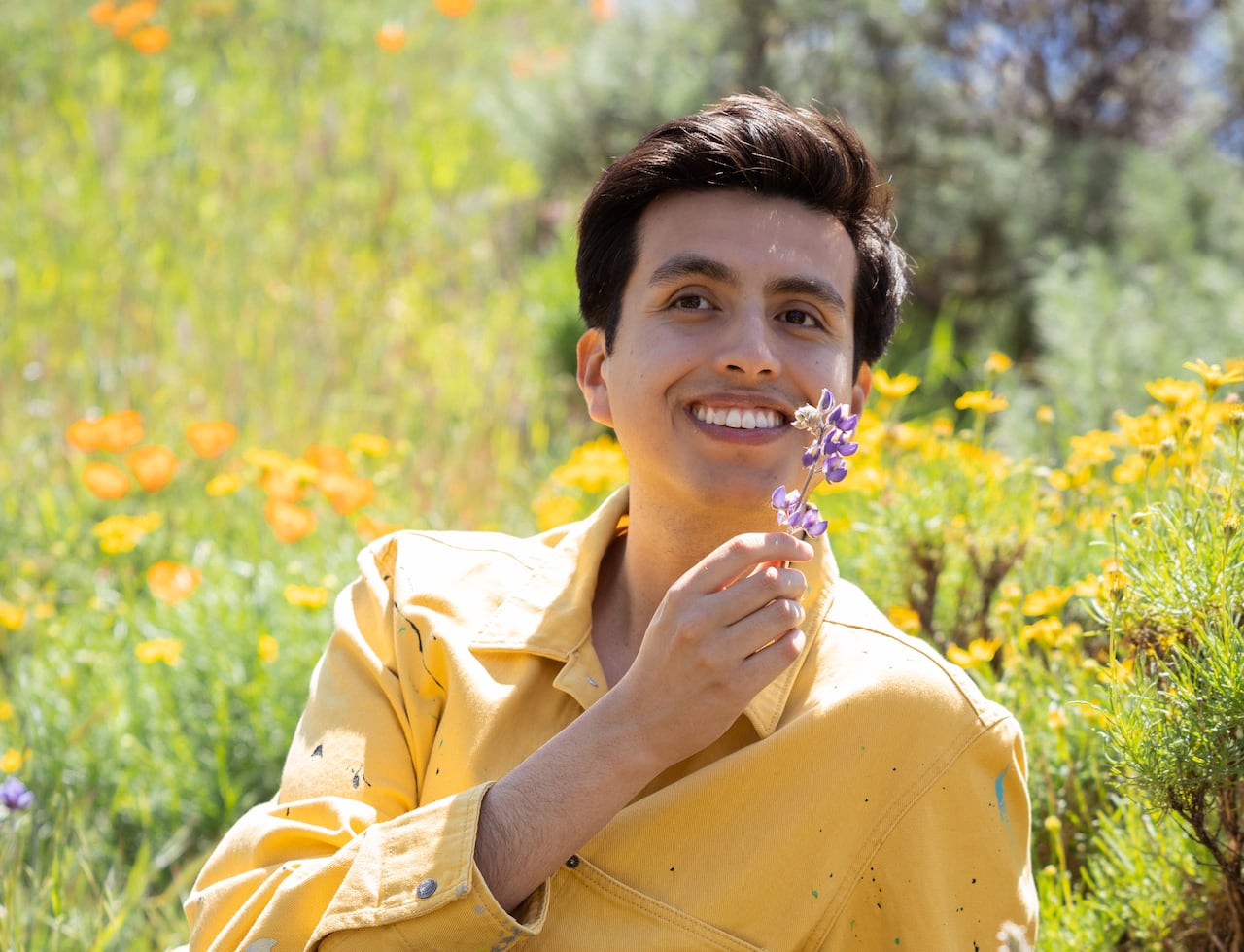 Man in yellow shirt holds a flower in a field of flowers