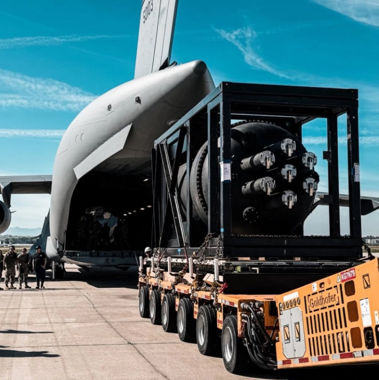 Large cylindrical object being fed into a big plane from truck bed