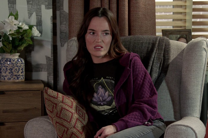 Jodie, in a purple hoody, looks narked in a scene from Coronation Street