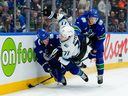 JJ Peterka of the Utah Mammoth is checked by Vancouver Canucks defencemen Tyler Myers and Elias Pettersson during second period of NHL game at Rogers Arena on Dec. 5.