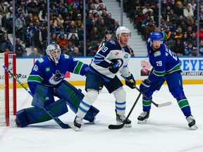 Nikita Tolopilo and Marcus Pettersson defend against Jonathan Toews of the Winnipeg Jets during the second period