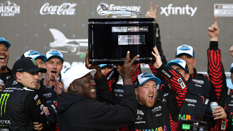 Tyler Reddick, driver of the #45 Chumba Casino Toyota, and Michael Jordan, NBA Hall of Famer and co-owner of 23XI Racing lift the Harley J. Earl Trophy in victory lane after winning the NASCAR Cup Series Daytona 500 at Daytona International Speedway on February 15, 2026 in Daytona Beach, Florida.