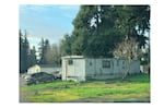 A manufactured home with cars parked out front.