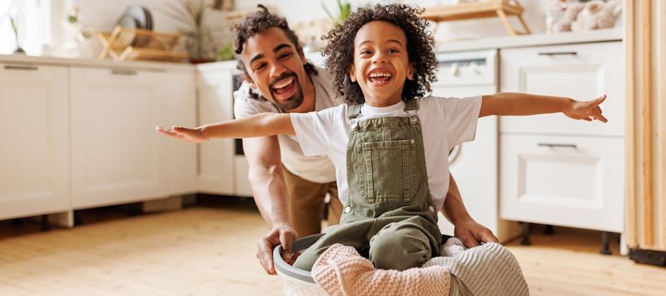 Dad plays with child -- pushing the child around in a laundry basket