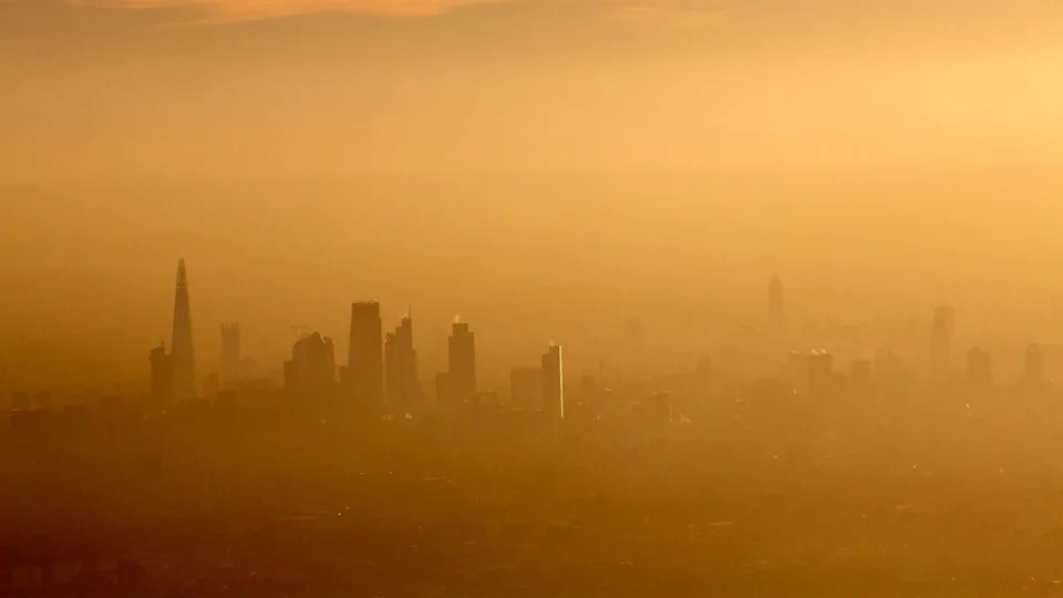 A yellow washed picture that is incredibly hazy, but you can see the outlines of buildings that make up the London skyline