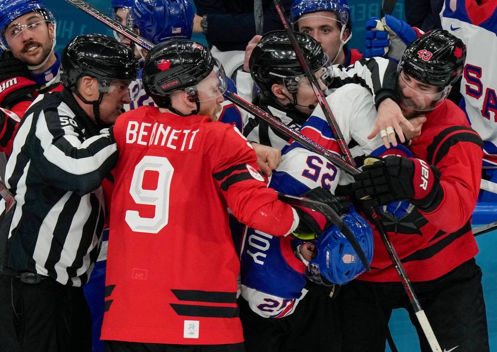 Referees try to break up a fight between Canada’s Sam Bennett (9), United States’ Charlie McAvoy (25) and Canada’s Tom Wilson (43) during the second period of the men’s ice hockey gold medal game at the 2026 Winter Olympics, in Milan, Italy, Sunday, Feb. 22, 2026. (Luca Bruno / The Associated Press)