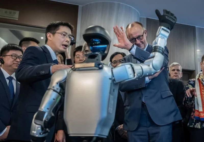 German Chancellor Friedrich Merz visits the company Unitree Robotics in Zhejiang province and is given a tour of the showrooms by founder and Managing Director Wang Xingxing (L). The company is known for its humanoid robots. Michael Kappeler/dpa