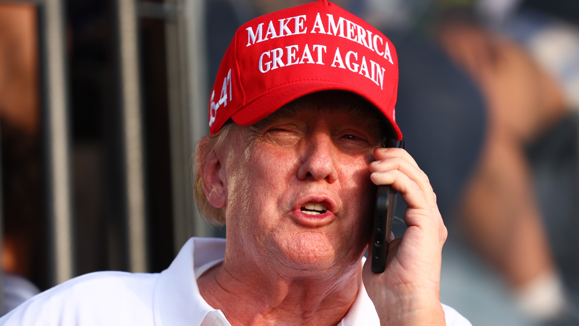 Donald Trump with phone wearing a red hat