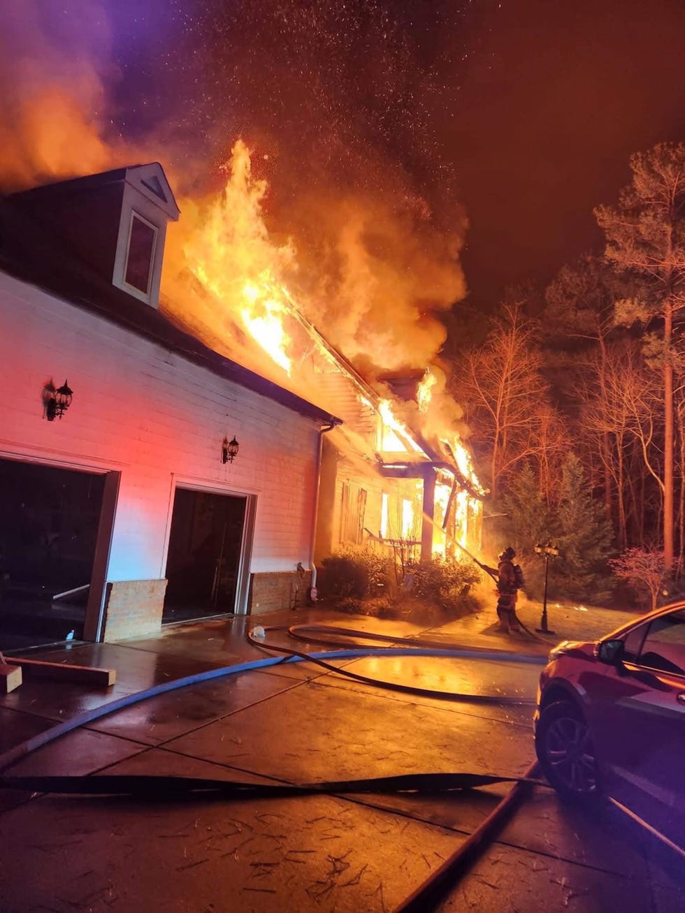 house engulfed in flames with a firefighter battling the fire