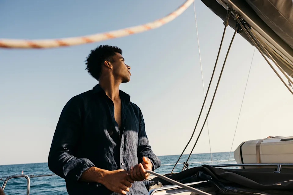 Person steering a sailboat on open water, looking at the horizon, capturing a sense of exploration and freedom in a work and money context