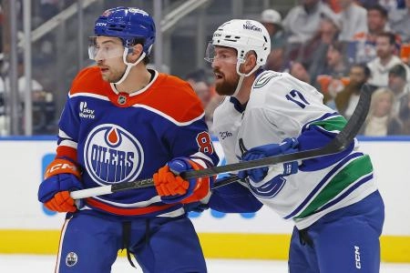 Oct 11, 2025; Edmonton, Alberta, CAN; Edmonton Oilers forward Andrew Mangiapane (88) and Vancouver Canucks defensemen Filip Hornek (17) look for a loose puck during the first period at Rogers Place.