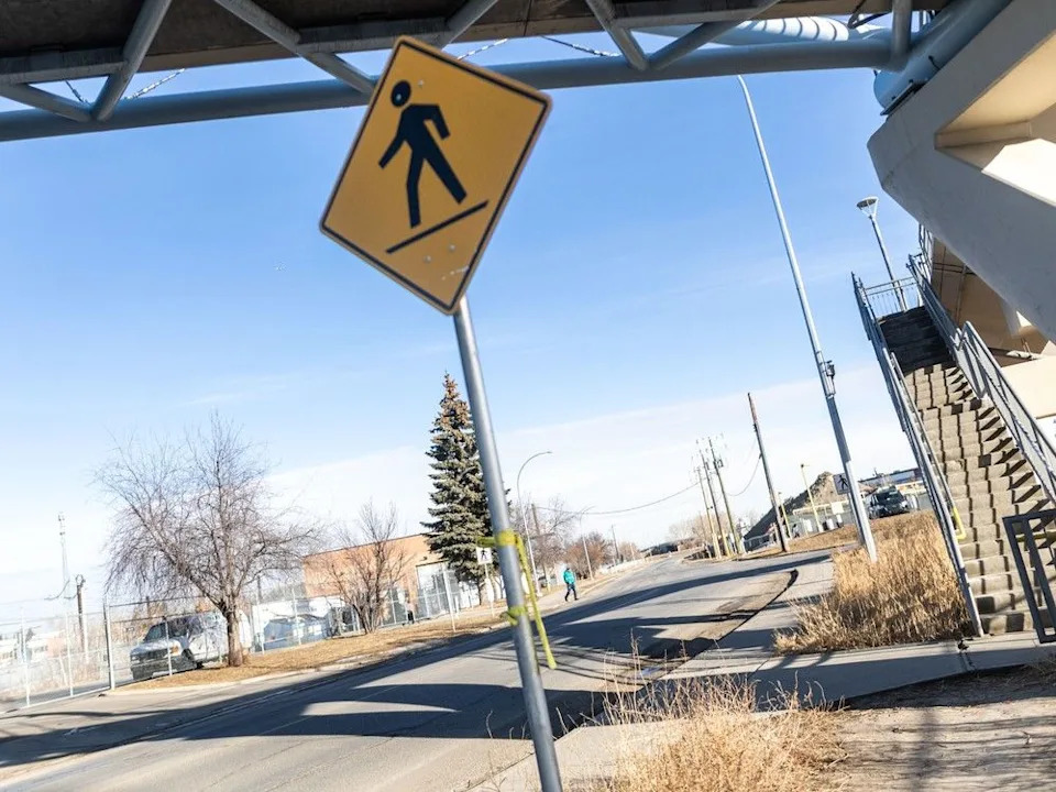 Police tape hangs on a crosswalk sign on Horton Road in Calgary on Monday, Feb. 16, 2026, where a fatal collision claimed the life of a toddler in a stroller the night prior.