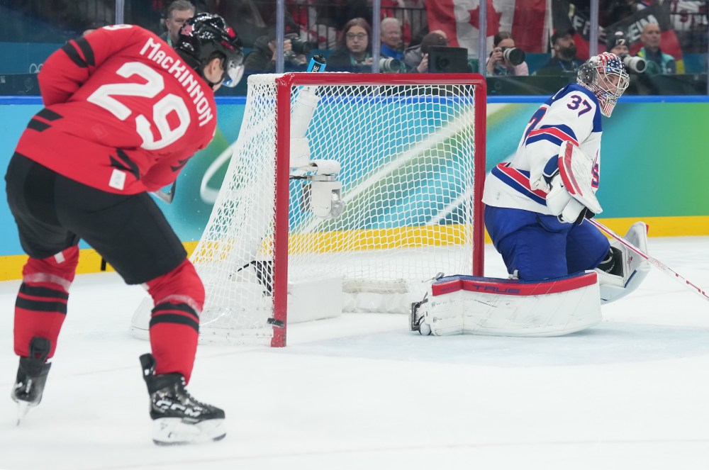 United States goalie Connor Hellebuyck (37) looks on as Canada's Nathan MacKinnon's shot misses the open net during third period of the men's gold medal hockey game at the 2026 Winter Olympics, in Milan, on Sunday, February 22, 2026. THE CANADIAN PRESS/Nathan Denette