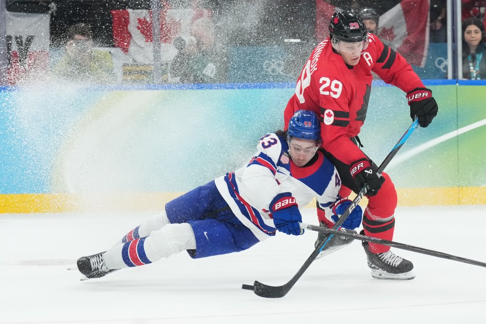 United States' Quinn Hughes (43) and Canada's Nathan MacKinnon (29) battle for the puck during third period of the men's gold medal hockey game at the 2026 Winter Olympics, in Milan, on Sunday, February 22, 2026. THE CANADIAN PRESS/Nathan Denette