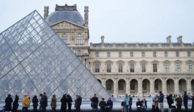 FILE - People wait for the Louvre museum to open as employees at the Louvre Museum vote to extend a strike that has disrupted operations at the world