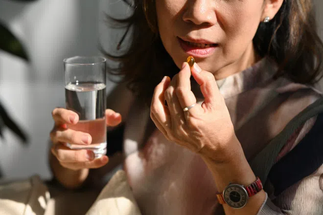 Best supplements for beautiful skin in Singapore: Elderly woman taking a fish oil supplement