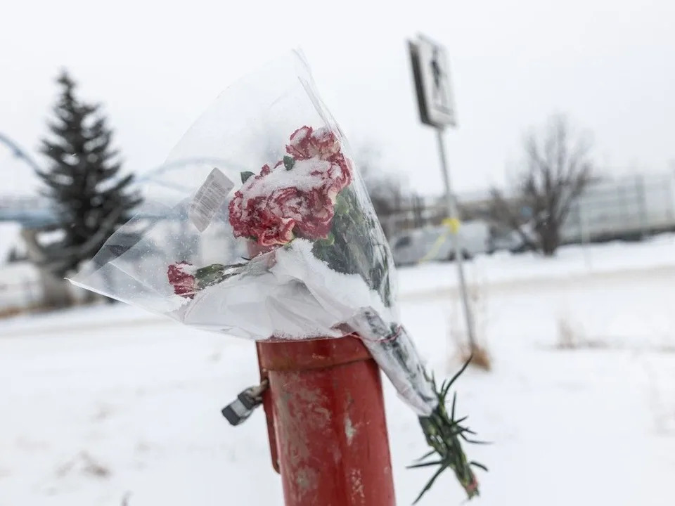 Flowers are seen at a crosswalk on Horton Road S.W. in Calgary on Tuesday, Feb. 17, 2026, where a collision claimed the life of a two-year-old in a stroller last Sunday.