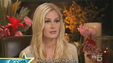 A person with long blonde hair speaking in an interview setting. The caption reads: "You could say I'm broke."