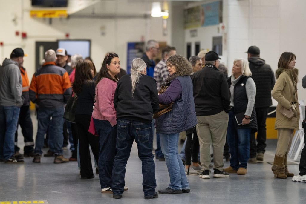 Residents of Olds, Alberta, talk in small groups at a community centre during an information session about a proposed data centre.