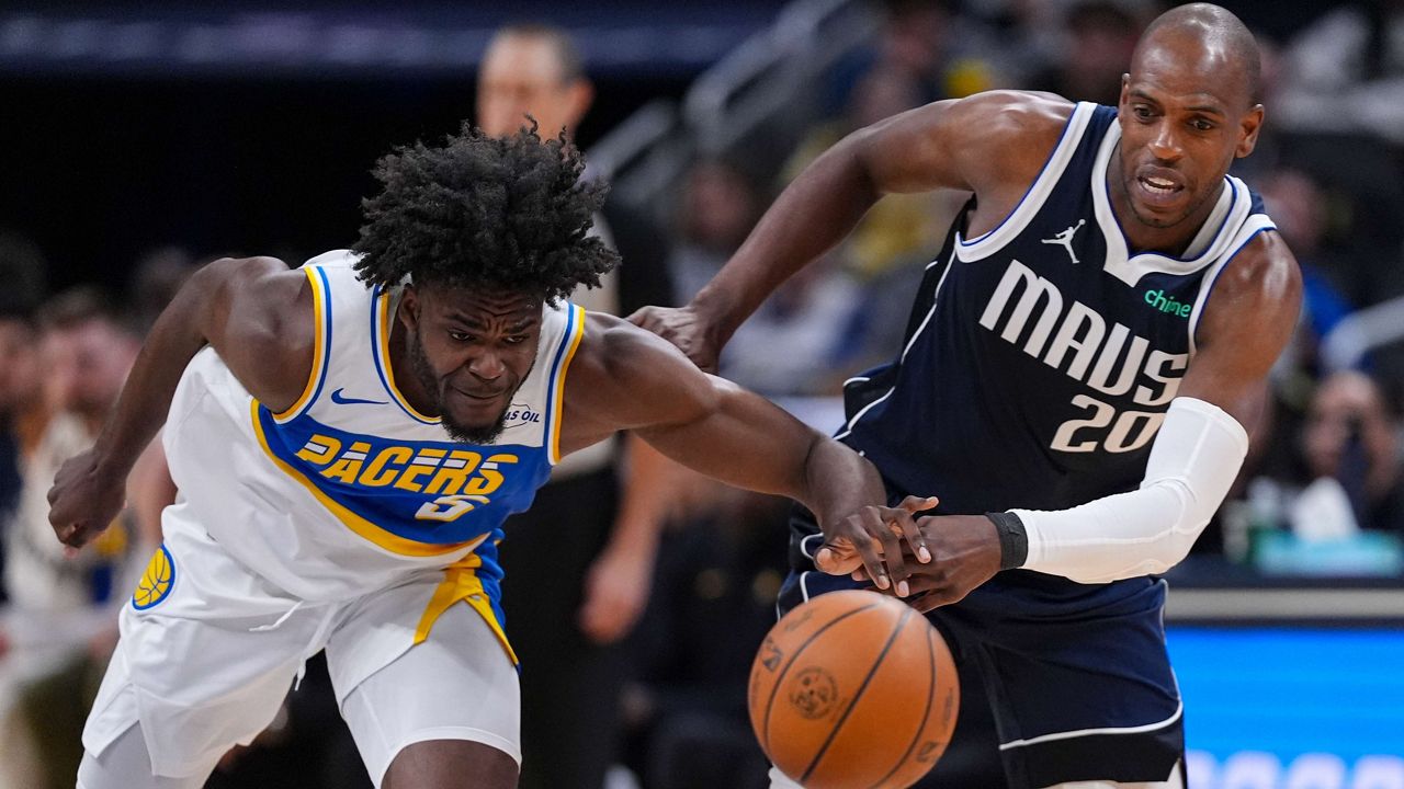 Indiana Pacers forward Jarace Walker (5) and Dallas Mavericks forward Khris Middleton (20) go for a loose ball during the first half of an NBA basketball game in Indianapolis, Sunday, Feb. 22, 2026. (AP Photo/Michael Conroy)