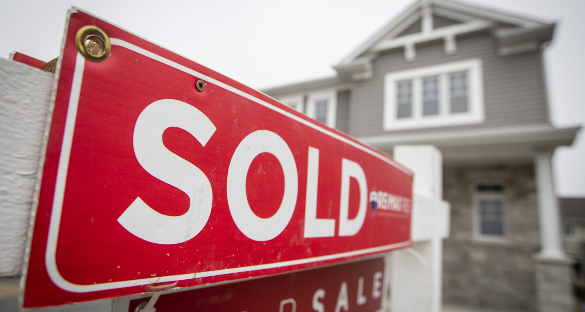 A real estate for sale sign in front of a house in Kingston, Ontario, illustrating real estate market activities.