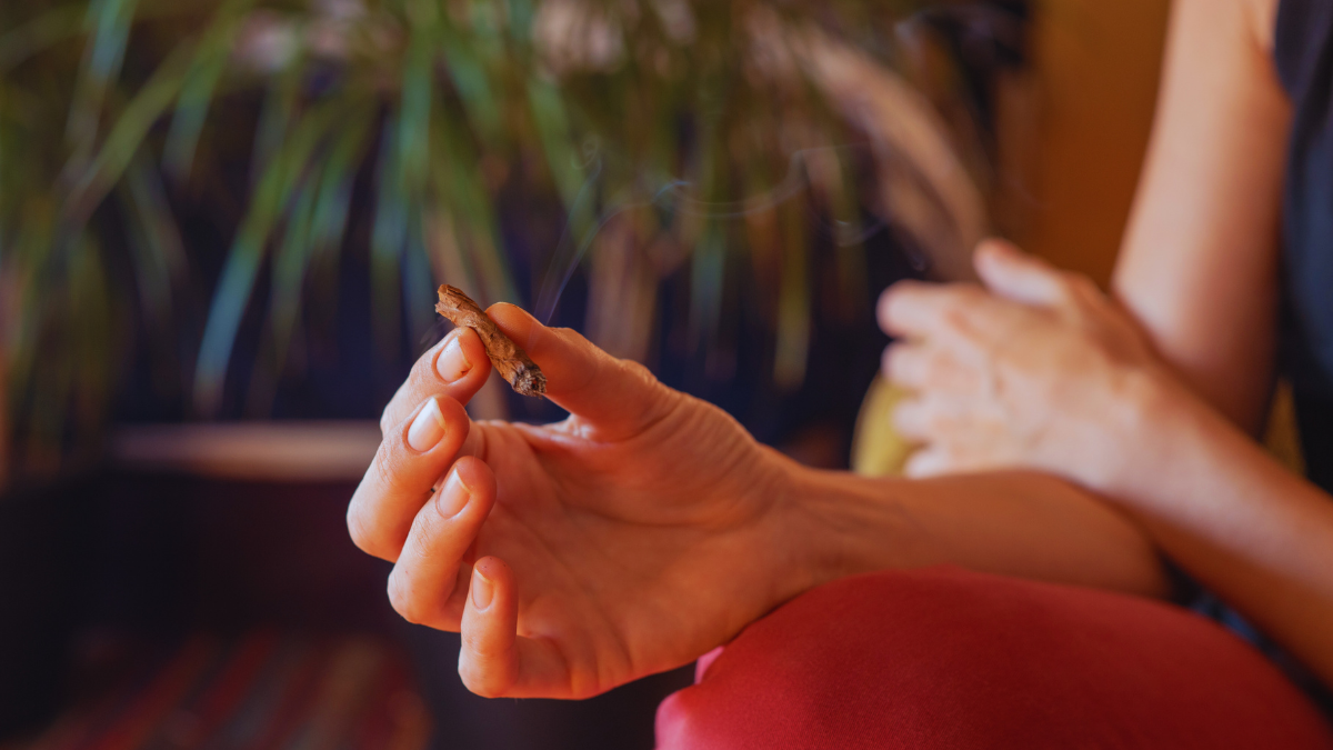 A woman holds a cannabis joint in her hand.