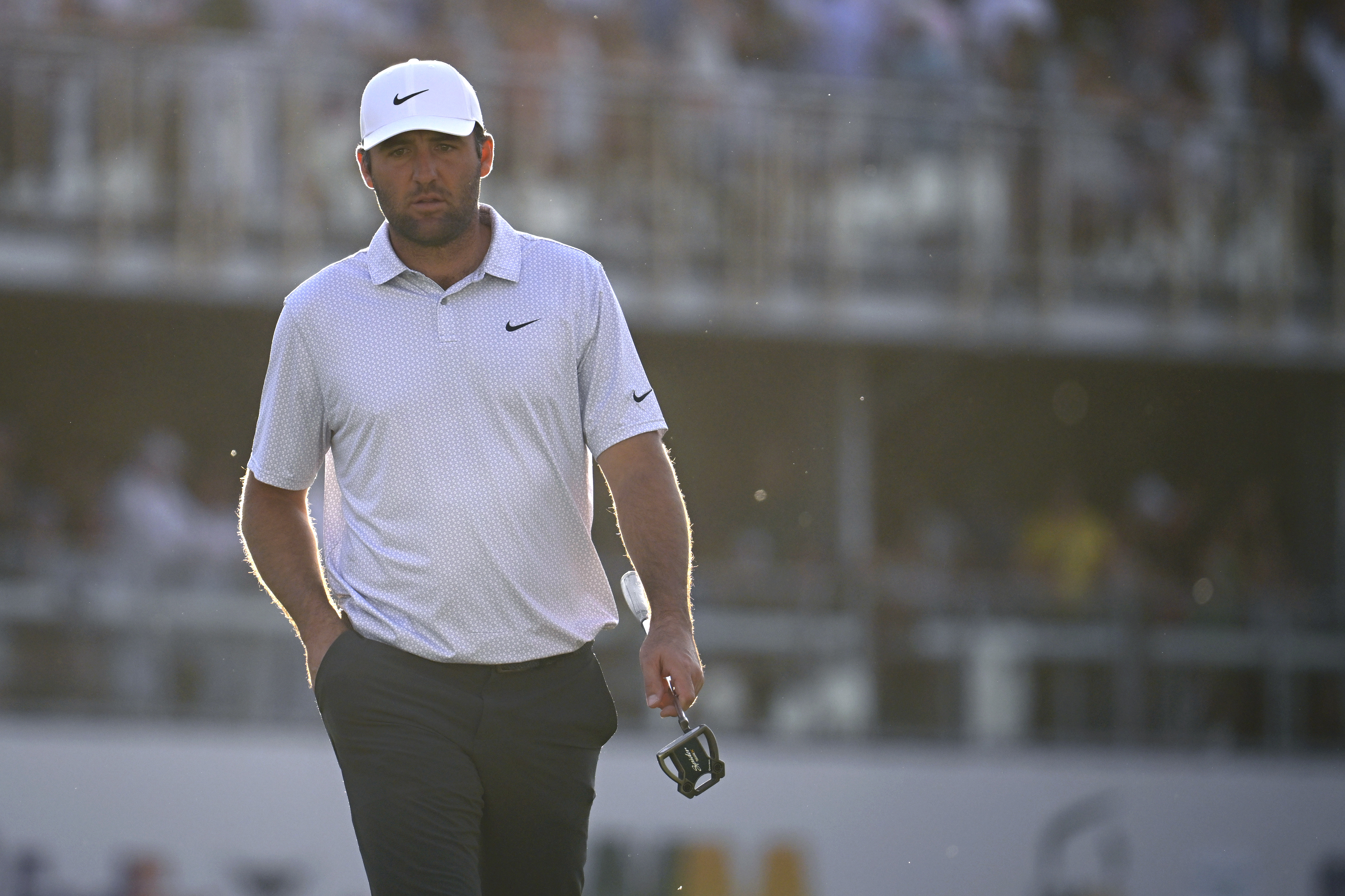 Scottie Scheffler walks off the green holding a putter