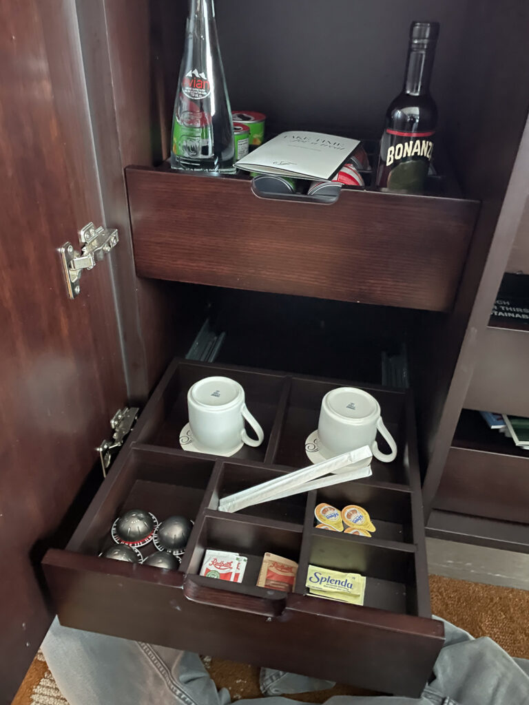 Coffee sundries in a drawer, plus a bottle of water and a bottle of wine