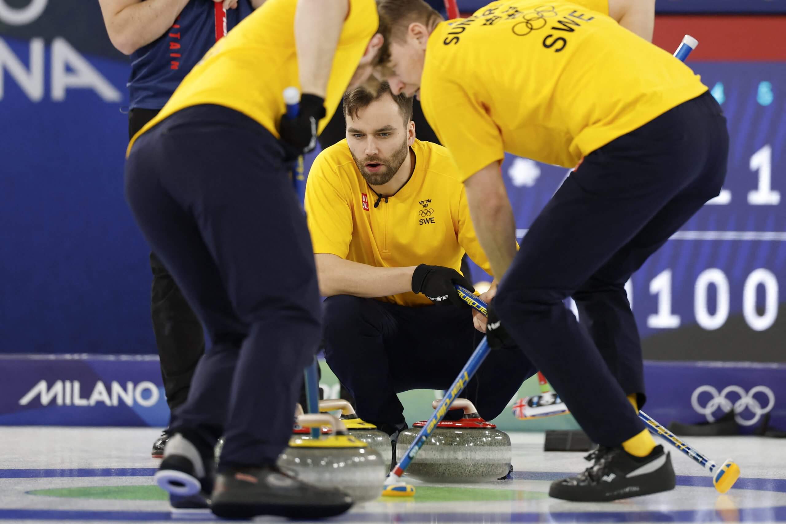 The Swedish men's curling team sweeps ahead of its stone, with Oskar Eriksson framed by his teammates.