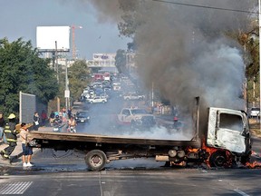 Firefighters extinguish a burning truck set on fire by organised crime groups in response to an operation in Jalisco to arrest a high-priority security target, at one of the main avenues in Guadalajara, state of Jalisco, Mexico, on February 22, 2026.