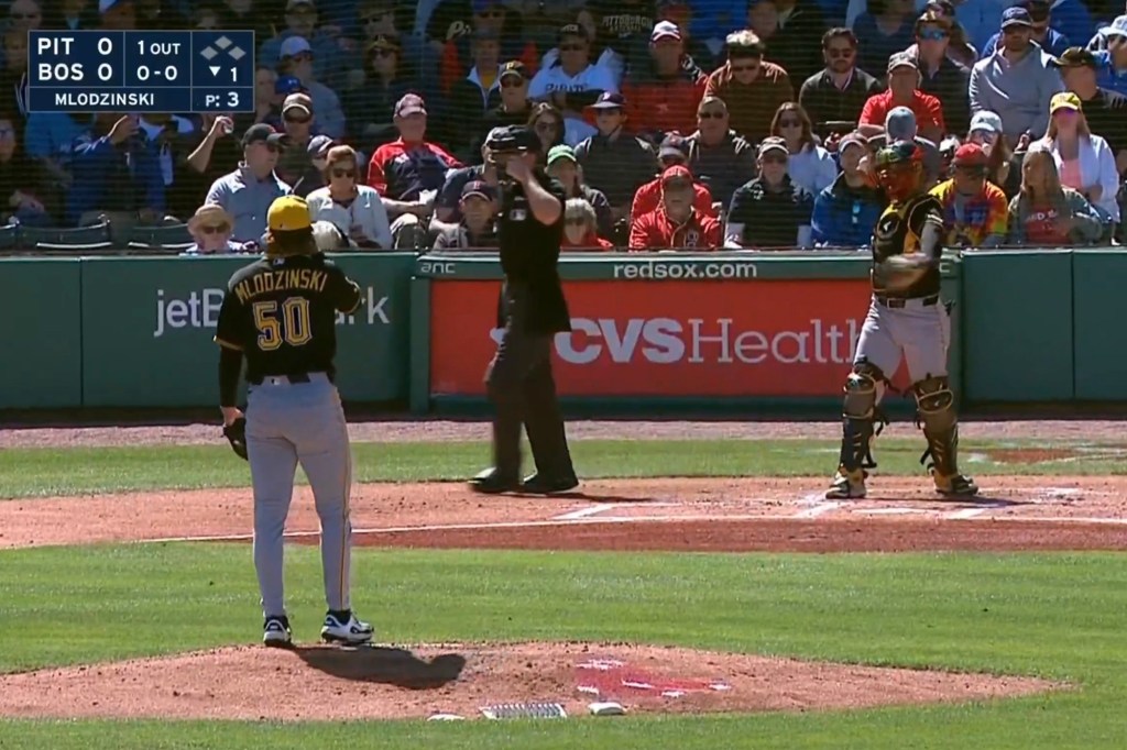 A baseball pitcher, catcher, and umpire on the field, with a scoreboard showing the Pirates and Red Sox are tied at 0.