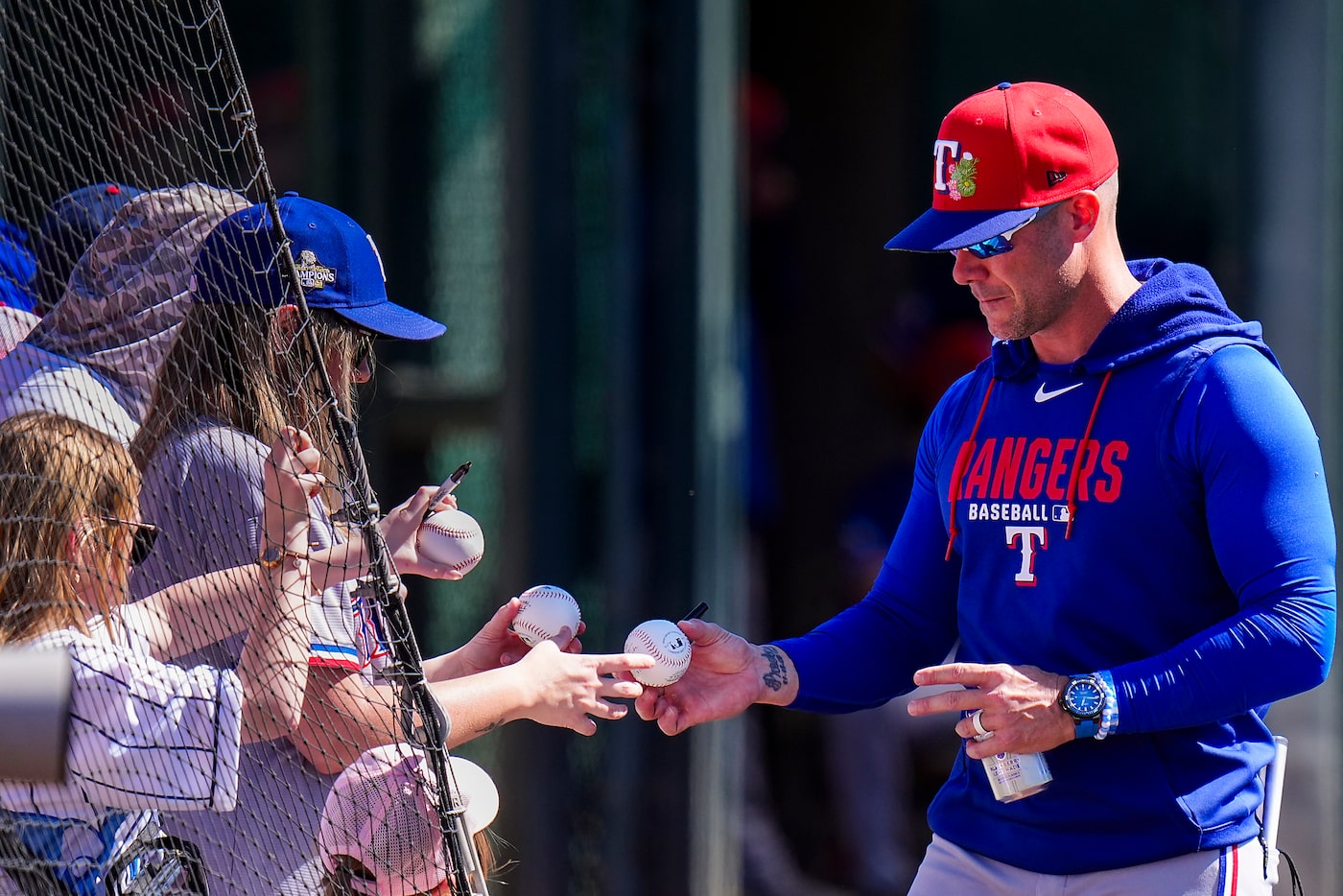Texas Rangers manager Skip Schumaker signs autographs before a spring training game against...