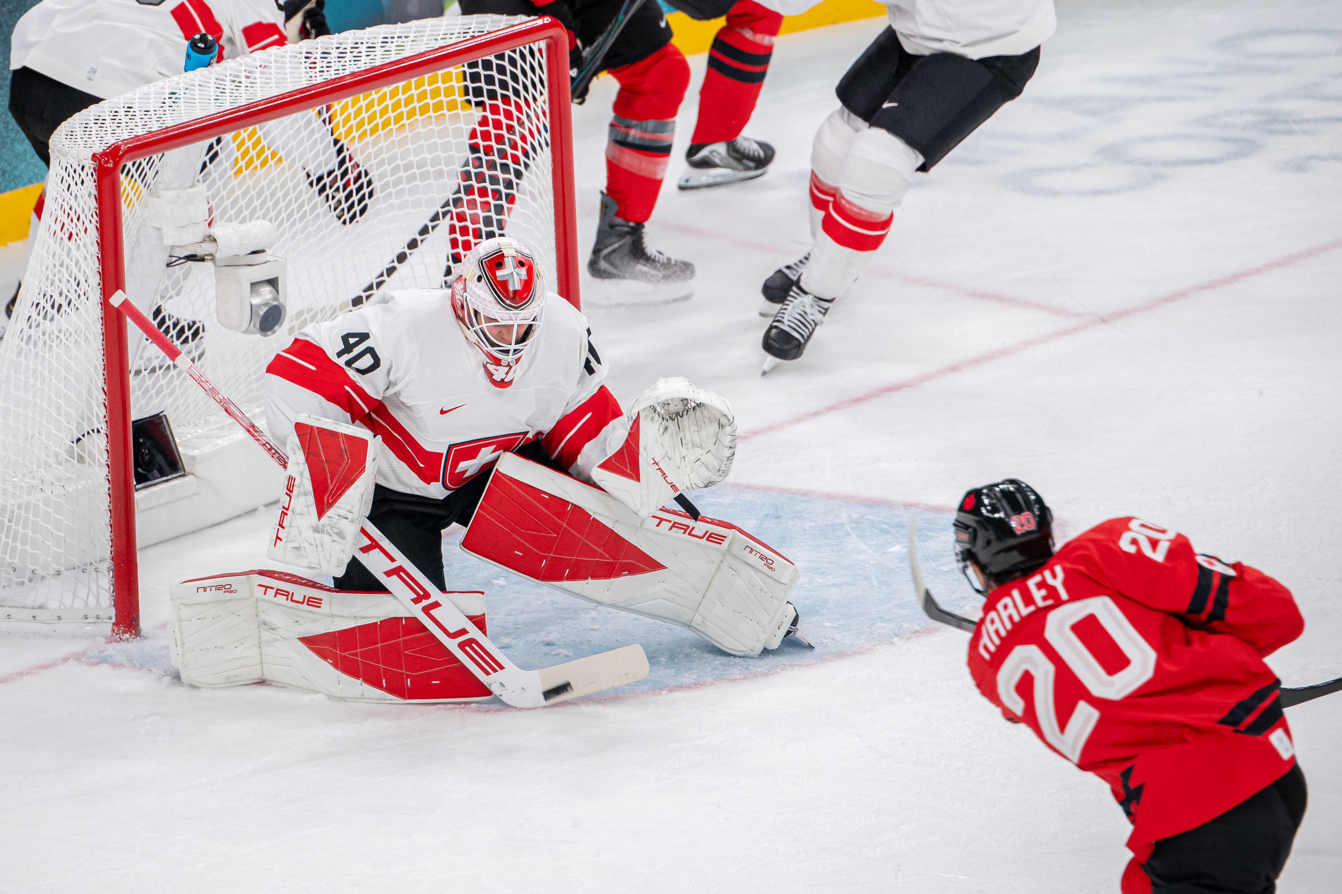 Thomas Harley #20 of Canada scores a goal against Sandro Schmid #40 of Switzerland during the Men's Preliminary Group A match between Canada and Switzerland on day seven of the Milano Cortina 2026 Winter Olympic games at Milano Santagiulia Ice Hockey Arena on Feb. 13, 2026 in Milan, Italy. (Photo by RvS.Media/Robert Hradil/Getty Images)
