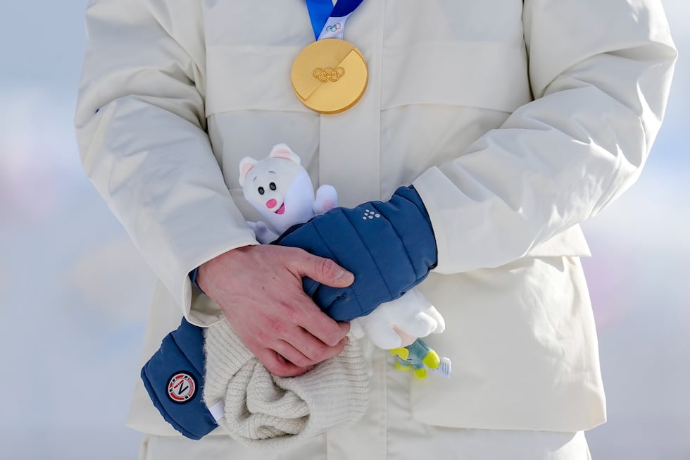 Jens Luraas Oftebro, of Norway, stands on the podium holding the Games mascot Tina after...