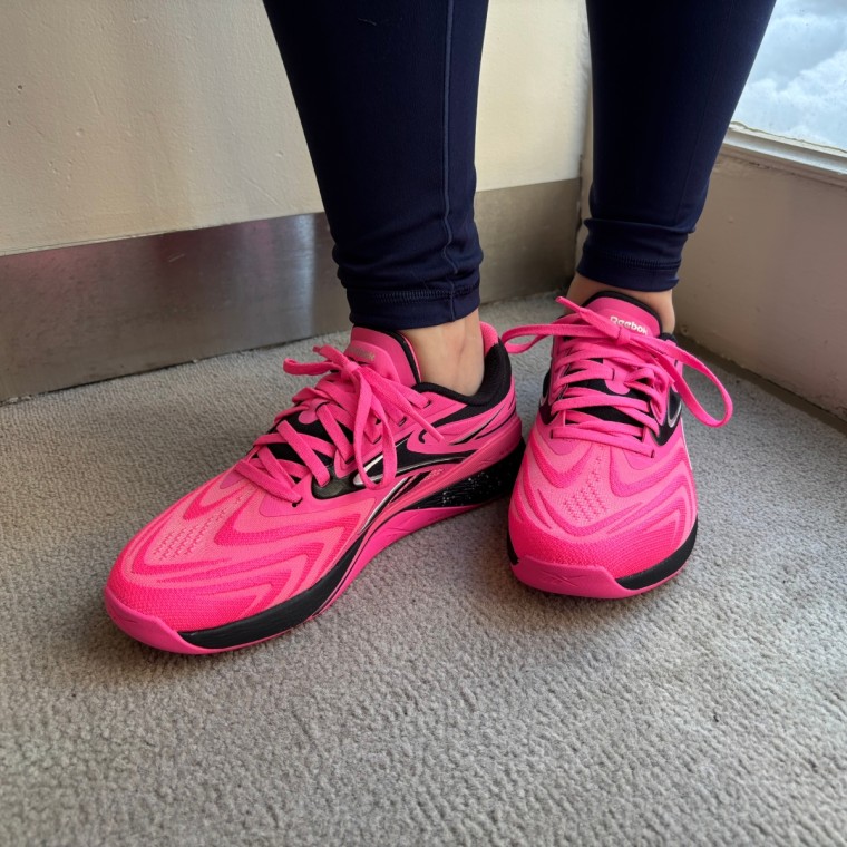 A close-up shot of someone wearing pink Reebok Nano X5 Edge training sneakers.