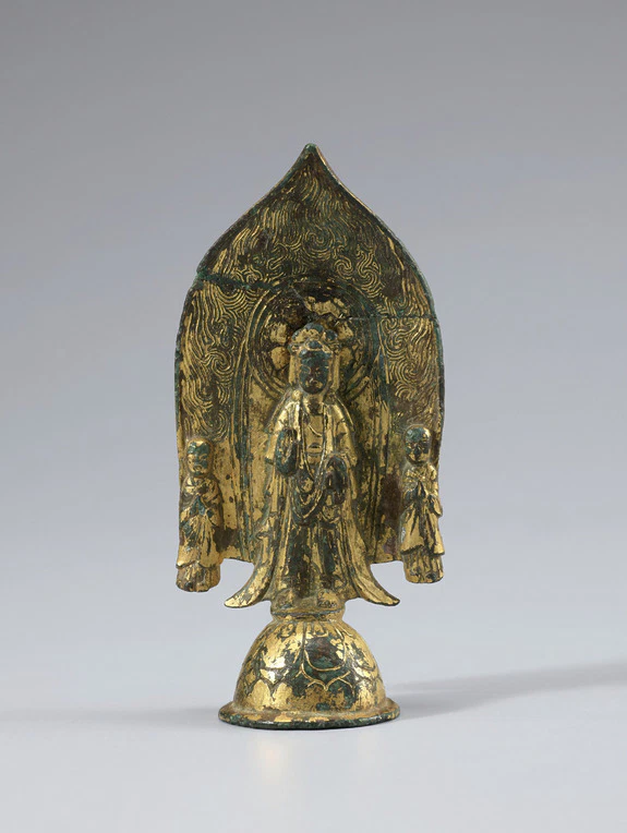 Ancient golden Bodhisattva statue with intricate detailing and two smaller figures, set against a plain background.