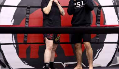 A girl and a boy wearing black shorts and shirts pose inside a combat sports ring.