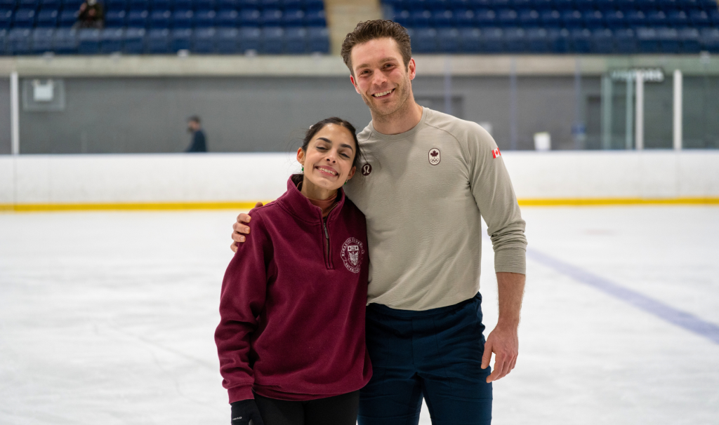 Olympic figure skaters Madeline Schizas and Trennt Michaud stand on the ice together and smile for a photo.