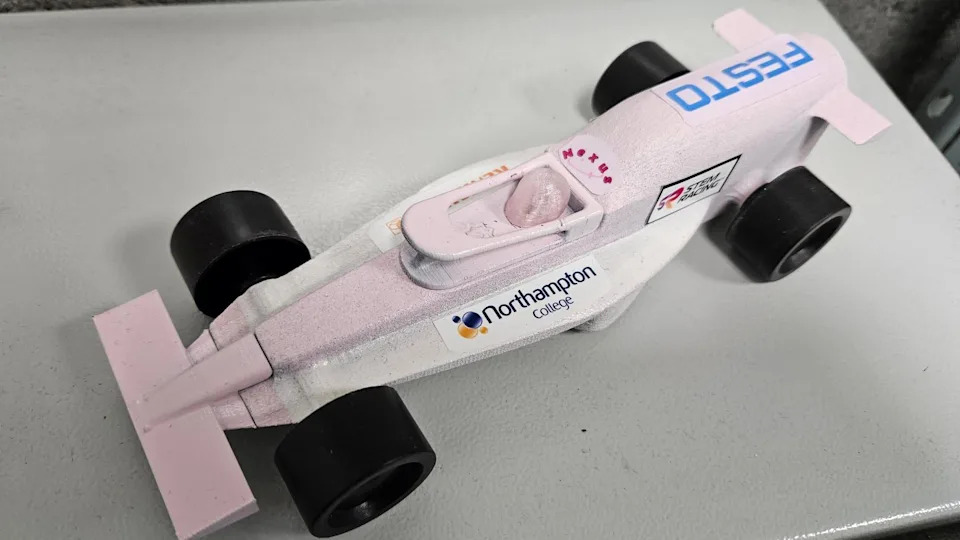A pink and white miniature F1-style car with "Northampton College" branding on the side.