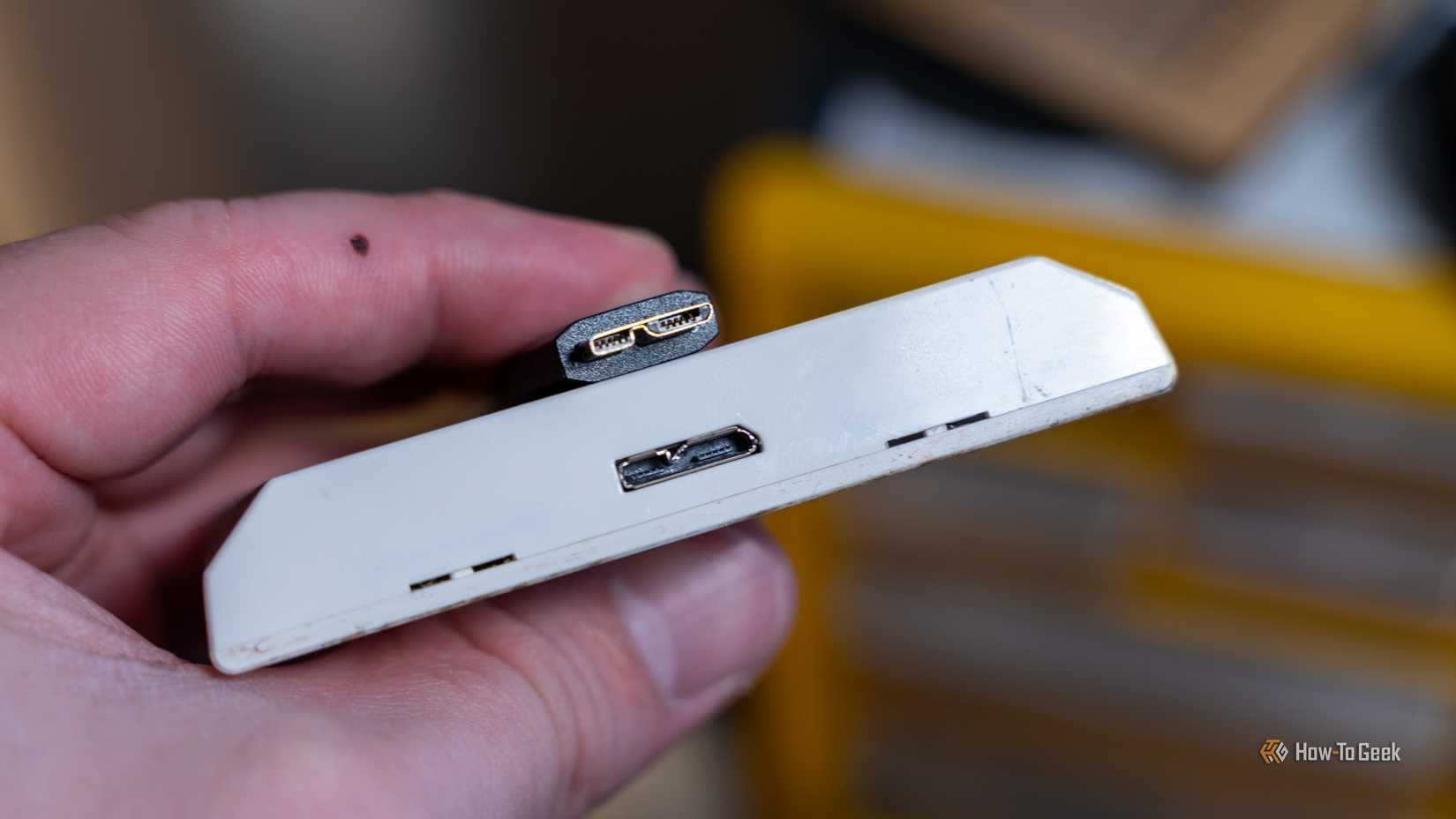 A person holding a device with a USB 3.0 micro-B cable and port.