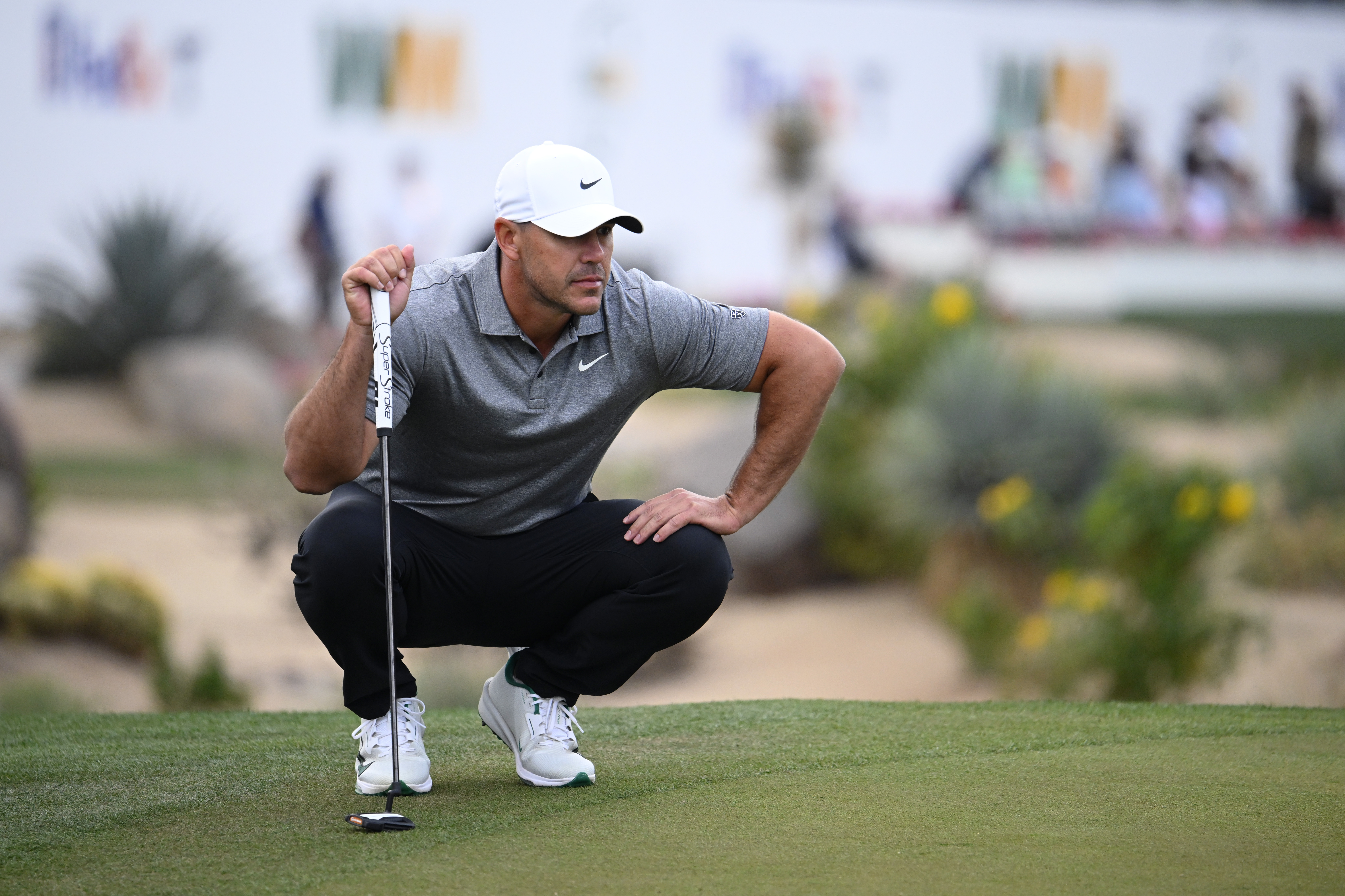 Brooks Koepka crouching down to read a putt
