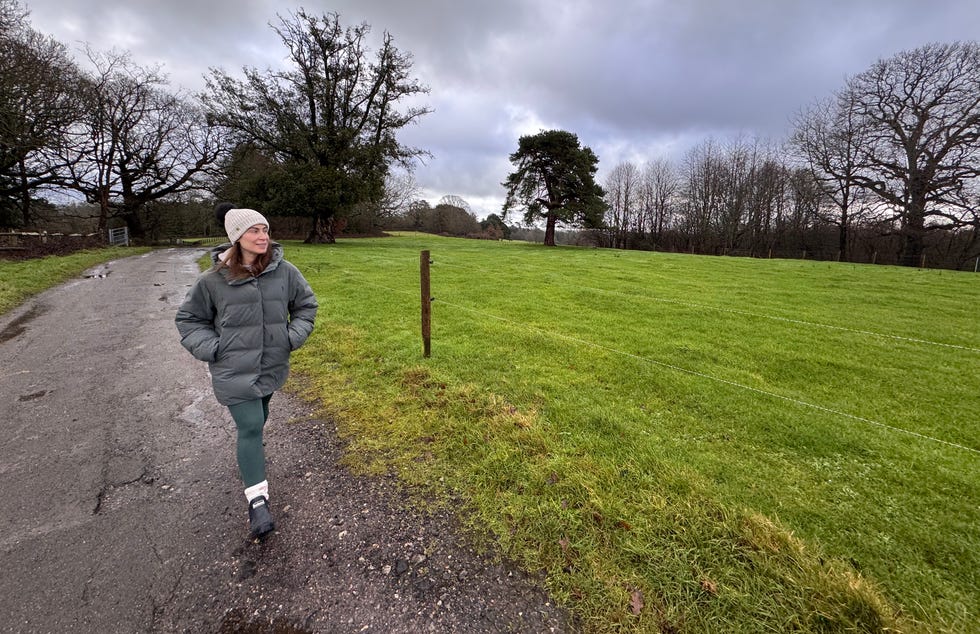 person walking on a rural path beside a grassy field person walking on a rural path beside a grassy field