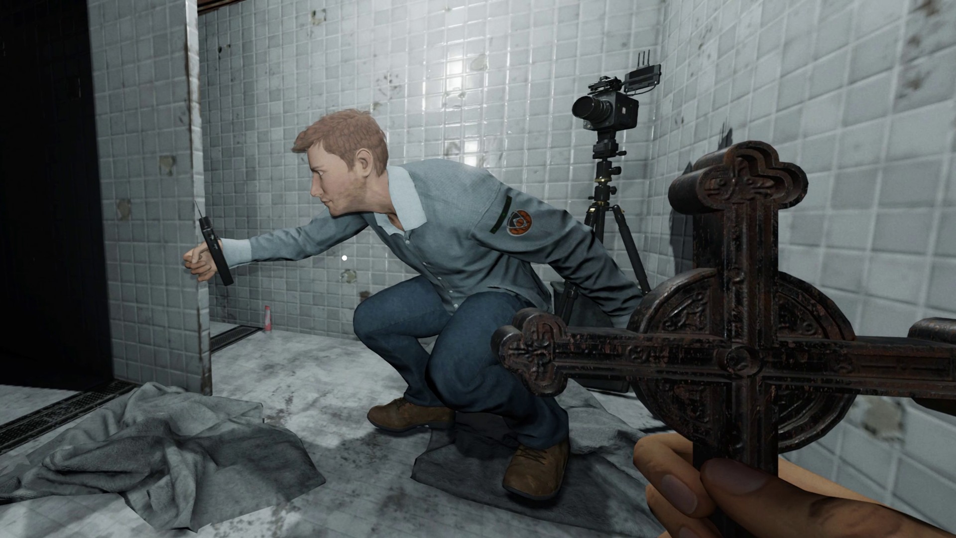 Phasmophobia player sitting in the bathroom holding a Spirit Box, the other player is holding a Crucifix looking at them.