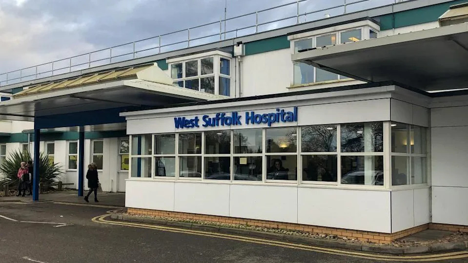 The outside of a West Suffolk hospital. It's a 1960s' building and has a big sign in blue writing saying West Suffolk Hospital.