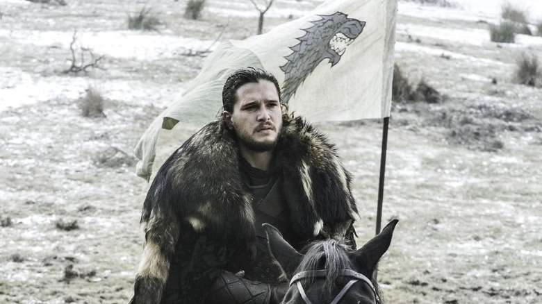 Jon Snow, riding a horse into battle with a banner in Game of Thrones.