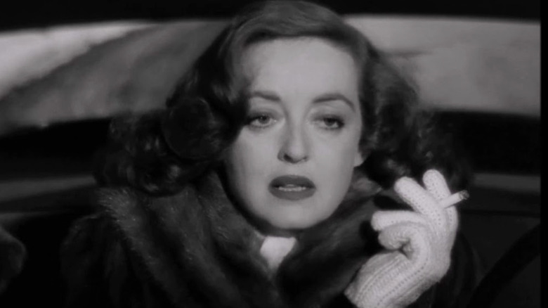 Bette Davis as Margo Channing smoking in a car in All About Eve